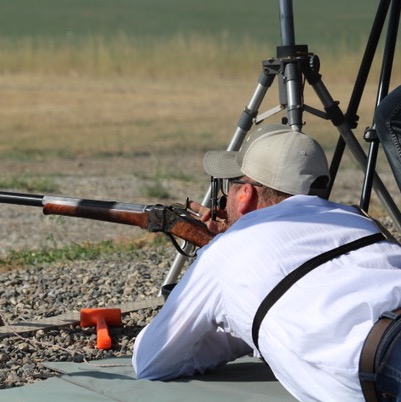 The shop's owner shooting a single-shot rifle prone off cross-sticks.